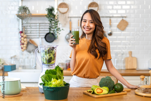 Portrait of beauty healthy asian woman making green vegetables detox cleanse and green fruit smoothie with blender.young girl drinking glass of smoothie, fiber, chlorophyll in kitchen.Diet, healthy.