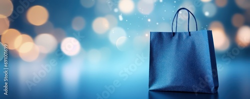 Blue paper shopping bag on blue background with bokeh. 