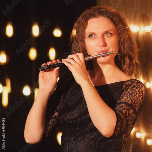 The female flautist, an accomplished musician, lit up the stage with her flute playing skills under the concert lights.