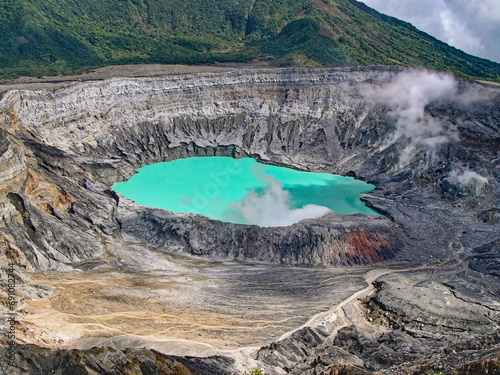 top view to the bright turquoise crater lake of the poas volcano with fumaroles in costa rica