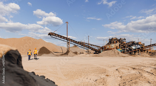 Team of industrial workers inspect sand quarry and check Industry machine for stone crusher, belt conveyor on open pit mine