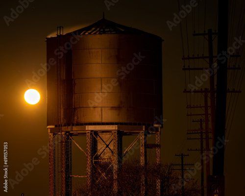 Railroad water tower at night with a full moon