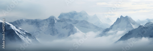 a panoramic view of snowy mountains with snow covered peaks covered with fog and snow in winters