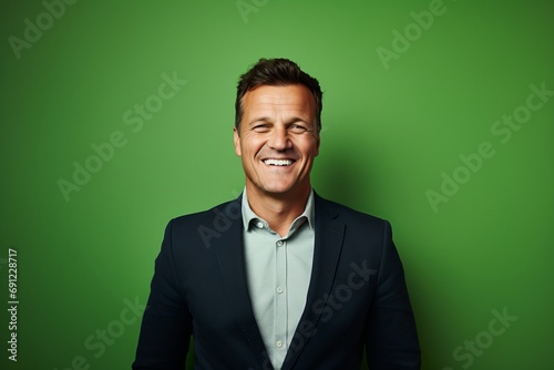 Portrait of a smiling mature businessman standing against a green background.