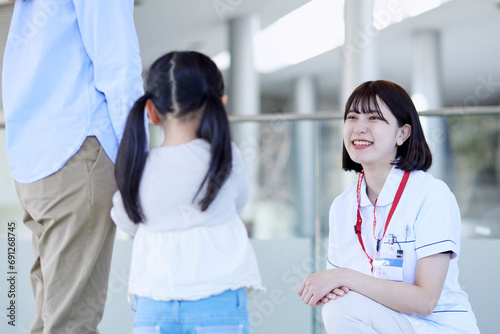 病院内にて話す笑顔の看護師と患者の子供