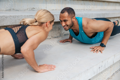 Athletic man and woman training doing push-ups outdoor.