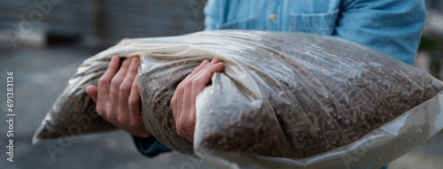 Man holding bag with wood pellets, pellet fuels manufactured in wood pellet line. Reusing wooden industrial waste.