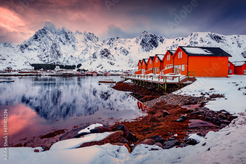 Norwegian red houses in Ballstad town on the shore of Norwegian sea. Dramatic sunseton Lofoten Islands archipelago, Norway, Europe. Life over polar circle. Traveling concept background..