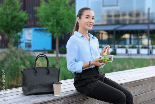 Smiling businesswoman eating lunch during break outdoors