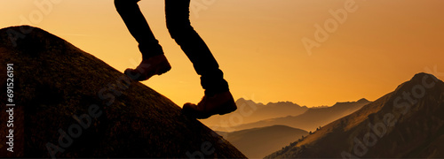 Beine mit Bergstiefeln auf einem Berggipfel im Gegenlicht
