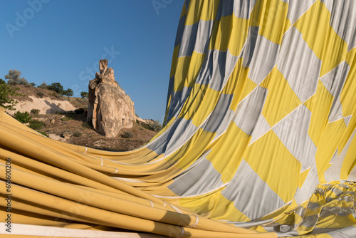 deflating hot air balloon with a fairy chimney in the background, Cappadocia, Turkey