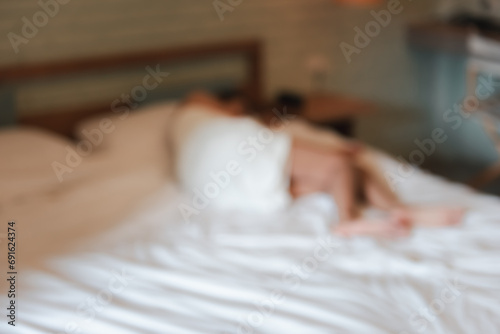 Blurred image of young woman wearing white towel lying on bed in room Victims of human trafficking or prostitution. Concept of against sexual services in tourism.