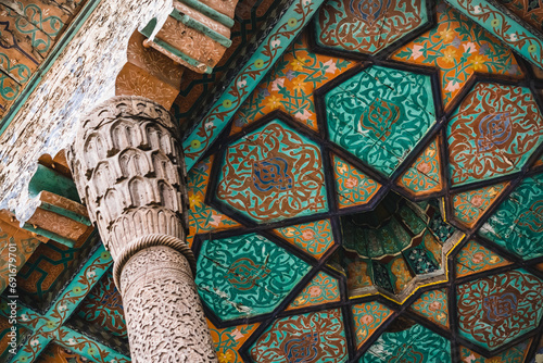 Wooden column support on the facade of a building supports the roof in the ancient city of Khiva in Khorezm, wood carvings and traditional patterns on the ceiling, interior