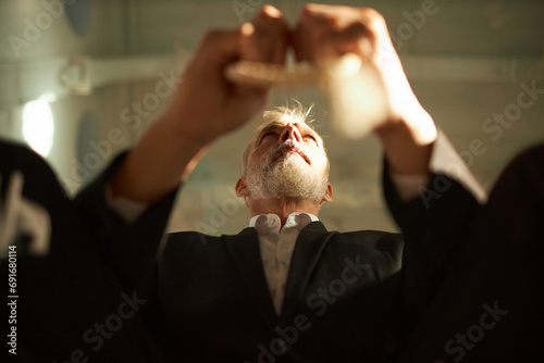 Low angle view at bearded senior man praying in church and holding rosary beads