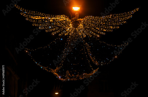 A large structure of lamps and garlands in the shape of an angel hangs on a street in the winter night in the city of Lviv in the country of Ukraine. Christmas, New Year decor, copy space.