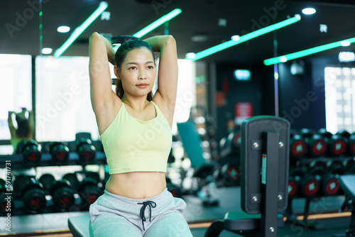 Active Asian sportswoman doing a weight training workout in indoor gym, Asian beautiful woman lifting a dumbbell.