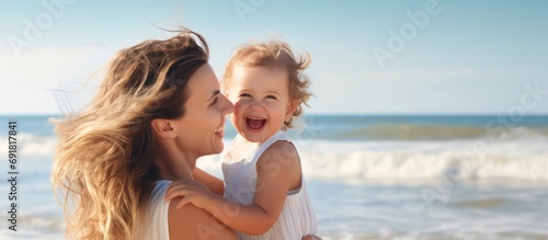 Joyful mother and baby embrace and have fun at the beach.