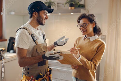Smilng young woman signing document while communicating with handyman at the kitchen