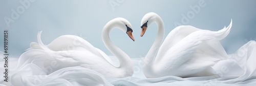 A duo of graceful swan sculptures creating a heart silhouette against gently folded silk cloth