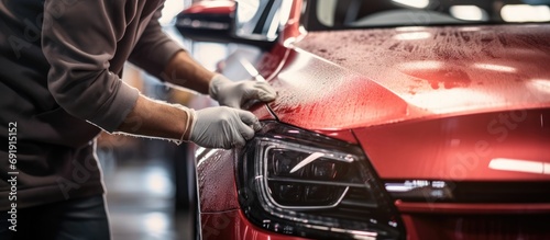 closeup shot of a car specialist cleaning a red car at the repair shop High quality photo. Copy space image. Place for adding text
