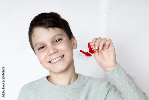Boy smiling with tooth retainers in hand. Concept of crooked teeth correction and bite correction in children.