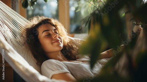 Relaxed young woman resting in comfortable hammock at home