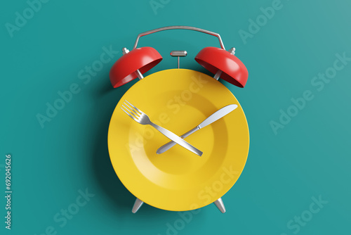 Yellow dining plate, silver knife and fork replacing the body, hour hand and minute hand of an alarm clock respectively. Illustration of the concept of mealtime