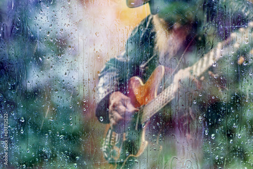 Fondo abstracto de guitarra y música country . Tocar en la guitarra canción detrás de la ventana con gotas de agua en un día lluvioso. Música triste para el camino de viaje.