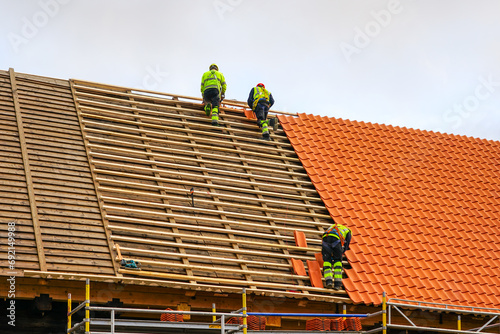 Clay tile roof replacement, three workers laying new clay tile roof