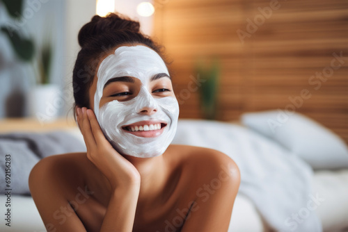 Beautiful happy cheerful girl applied beauty facial mask . Woman chilling relaxing on couch at home