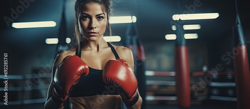 Fit Caucasian trainer supports sportswoman boxing in gym. Attractive athletes use Muay Thai gloves for health in stadium club.