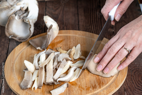 A woman slices an oyster mushroom on a cutting board. Cooking fresh wild mushrooms.