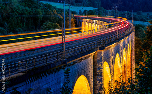 Panorama with “Bekeviadukt“ bridge in Altenbeken Germany from 1853. Double track bent limestone railway viaduct on the main line Paderborn Warburg is a monument. Illumination at blue hour twilight.