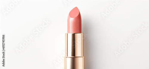 An peach fuzz color lipsticks top in a golden case on a white background. Make up a product show off. Copy space.