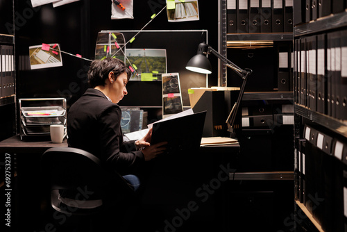 Federal investigator sitting at desk in arhive room late at night, working at mysterious crime case analyzing evidence. Private detective reading fbi confidential report discovery suspect research