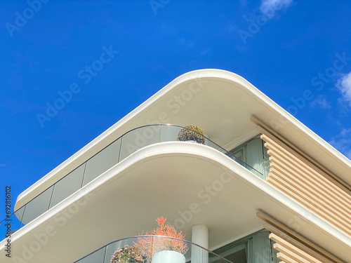 Summer white house on the beach with blue sky. Close-up of part of a house structure. Villa balconies and railings. Luxurious architecture. Exterior walls covered with lime.