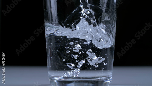 Water being poured into glass transparent cup in super slow-motion at 1000 fps in black background