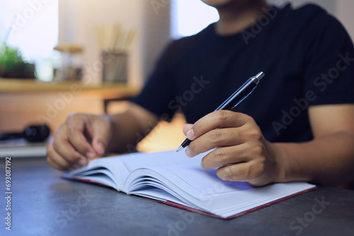 A man uses a pen to write on a notebook to write a memo or compose a song and review goals or plan topics for the next year