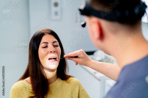 the ENT doctor examines the patient in the office of the clinic, checks the oral and nasal cavity and ear canals with professional instruments