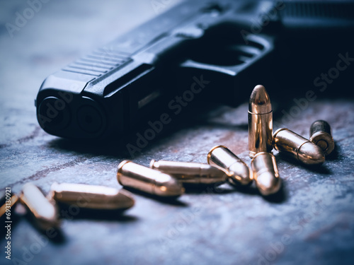 Hand gun with ammunition on dark background. 9 mm pistol military weapon and pile of bullets ammo at the metal table.