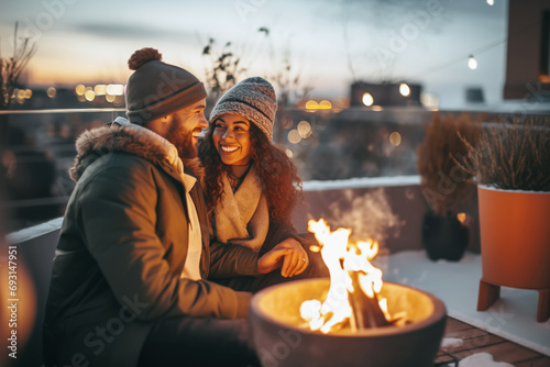 Happy couple having a romantic date on outdoor terrace with fire pit in winter