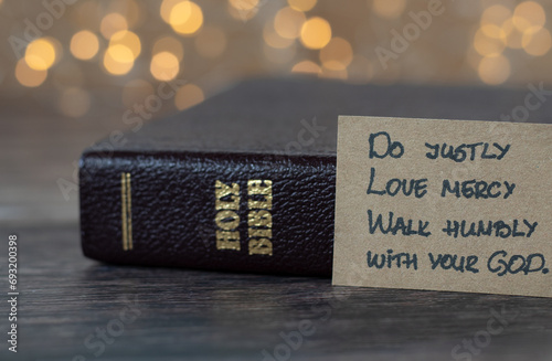 Do justly, love mercy, walk humbly with your God, handwritten biblical quote, Micah 6:8 and holy bible with bokeh background. Christian biblical concept of humility and obedience to Jesus Christ.
