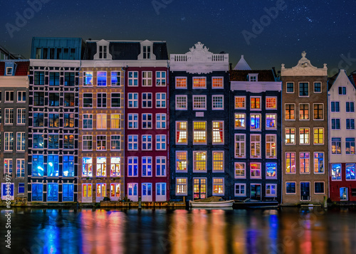 Amsterdam at night with dancing colorful houses at the Amsterdam canals in the Netherlands. colorful houses architecture in Amsterdam at night with colorful street lights and reflections in the canal