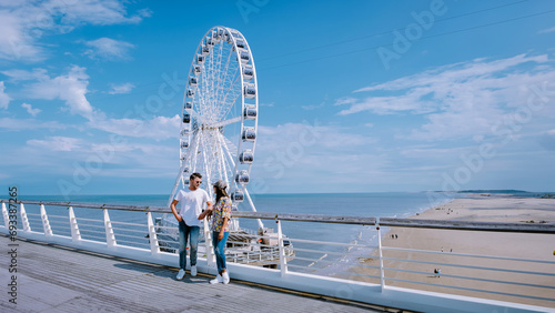 The Ferris Wheel The Pier at Scheveningen The Hague Netherlands on a Spring day, a man and a woman standing on the pier on the beach on a sunny day