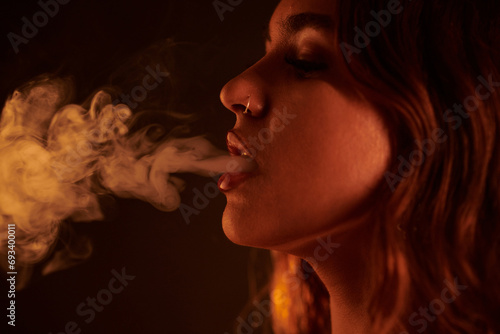 Young woman with piercing exhaling smoke of hookah