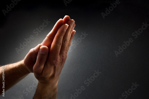 Praying man hands with palms together isolated dark