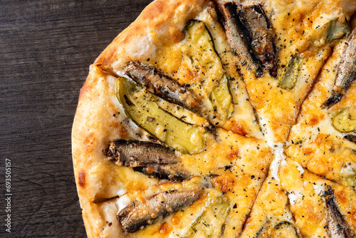 delicious pizza with sprats fish and pickled cucumber on wooden background