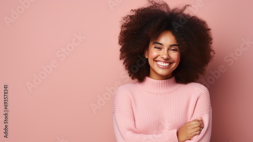 A woman with dark skin and curly hair is standing with crossed fingers and waiting for important news. she is wearing a casual jumper and her body language demonstrates a sweet desire,