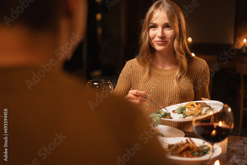 Young lovers couple having romantic dinner with candles and red wine at home