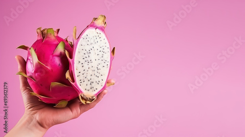 Hand holding sliced dragon fruit isolated on pastel background